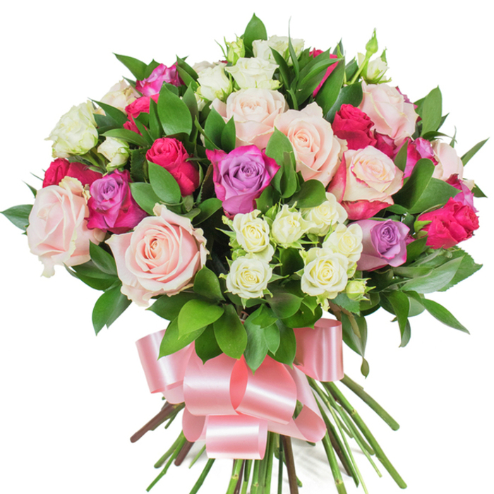 A lush, sculpted bouquet photographed on a pristine white background, composed chiefly of mixed roses and abundant green foliage that together create a dense, rounded silhouette. The arrangement foregrounds several large, fully opened roses in soft pastel pink and creamy white, each bloom revealing delicate petal textures and gentle central spirals. Bright magenta or deep fuchsia roses are interspersed to introduce vivid, joyful accents, while a scattering of delicate lavender roses contributes a subtle coolness to the overall warmth. Small spray roses - predominantly creamy with light yellow undertones - are tucked into the folds between larger blooms, introducing fine detail and layered depth to the composition. Glossy, elongated leaves, likely ruscus or salal, are woven through the flowers, their dark green surfaces providing a rich contrast that enhances petal colour and clarifies the bouquet's shape. The long stems are gathered in a neat hand-tie and bound with a wide, satin ribbon in a soft pink shade, tied into a generous bow whose smooth sheen reflects light and complements the arrangement's romantic character. The white studio background and soft, even illumination ensure every petal edge, leaf sheen, and ribbon fold is visible; the overall effect is one of fresh elegance and thoughtful craftsmanship. This bouquet communicates affection and celebration - equally suited to birthdays, anniversaries, Mother's Day or a heartfelt 'thank you' - and feels naturally at home for delivery to Stanmore addresses near the station or to homes around Canons Park.