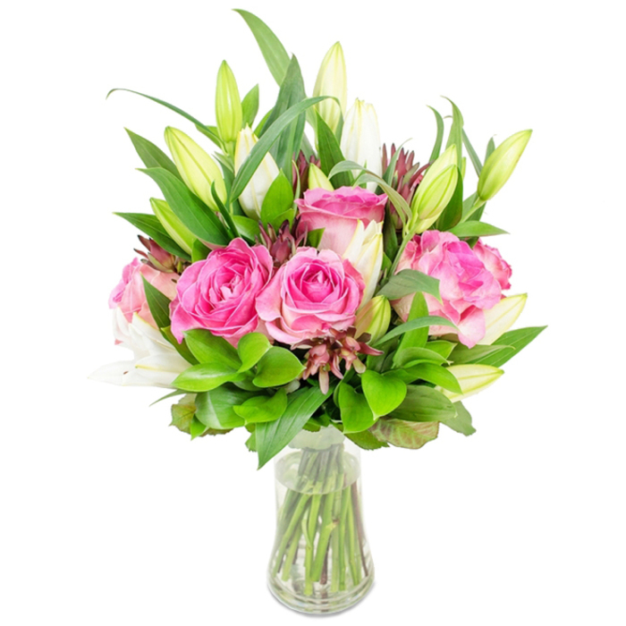 A lush, artfully balanced bouquet of deep pink roses and white lilies is displayed in a simple clear glass vase against a stark white background, allowing the flowers' natural colours and textures to become the image's sole focus. Prominent, fully bloomed roses sit at the heart of the arrangement, their soft, velvety petals folding into rich layers of fuchsia and blush that suggest both romance and vitality. White lilies thread upward through the mass of roses; several are composed as tight buds with pale green tips, promising later drama, while a few are beginning to open into elegant trumpet shapes that reveal their creamy interiors. Surrounding foliage - an abundance of deep green leaves, some broad and glossy, some fine and feathery - brims outward to create volume and a verdant backdrop that lets the pinks and whites pop. Subtle darker accents in the form of small burgundy buds or stems are interspersed to add contrast and depth without overwhelming the soft palette. The clear vase, classic and unobtrusive, displays crisp water and visible stems, underscoring the bouquet's freshness and the careful trimming that went into its arrangement. This composition reads as a celebration of seasonal blooms, a thoughtful present for Mother's Day or an anniversary, and would sit beautifully on a dining table after a weekend visit to Bentley Priory or a quiet afternoon in Stanmore's local cafes.
