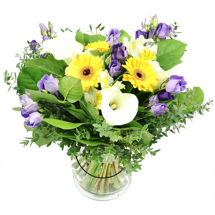 With the careful hand of a Stanmore florist, this mixed bouquet is a study in bright happiness, arranged in a clear glass vase that reveals the stems swimming in clean water. The backdrop is stark white, designed to let every hue breathe. The daisies are yellow Gerberas, their large heads radiating warmth, each punctuated by a dark center that anchors the visual field. White Calla lilies rise in elegant trumpets of white, their ivory trumpets adding clarity and space around the vibrant core. The Lisianthus, in shades from soft lavender to deeper purple, weave through the bouquet with a graceful, rosette-like delicacy, some blooms fully open, others still in bud, creating depth and a sense of movement. White Alstroemeria with subtle yellow or green streaks add delicate texture and brightness in between. The generous greenery, eucalyptus with its silvery sheen and broad evergreen leaves, gives the arrangement a lush, natural frame, a scent that is faint, fresh, and inviting. The stems are neatly aligned inside the glass vase, water clear, with a discreet black tie securing the composition, a signature touch from Flowers Stanmore. The overall feeling is one of modern elegance and unforced joy, ideal for celebrations, corporate gifting, or simply brightening a home. In Stanmore and the surrounding NW London neighborhoods, this bouquet is readily available for same-day delivery, bringing a touch of sunshine to doorsteps, receptions, and coffee corners alike. Every day, this bouquet travels with care.