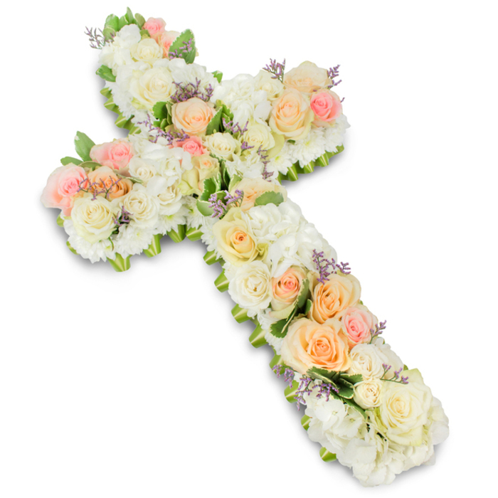 A large, cross-shaped floral tribute is presented against a pristine, high-key white background, the simplicity of the setting allowing every flower and curve to stand out with clarity. The Christian cross form is rendered entirely in flowers, with soft, rounded lines and no visible frame, giving the design a comforting, almost embrace-like presence. Abundant white and creamy ivory flowers make up most of the surface: multi-petalled hydrangea mounds or similar blossoms supply fullness, while classic roses and petite spray roses are nestled throughout to create a rich tapestry of petals. Among this calming field of white, carefully placed roses in soft pastel hues-gentle peach, warm apricot, and light blush pink-add subtle streams of colour, creating focal points that catch the eye along the arms and centre of the cross. Tiny, clustered filler flowers in a light lavender or pale purple tone appear like scattered sighs of colour, adding intricate detail without overwhelming the pastel harmony. Around the outer contour, modest touches of fresh green foliage peek out, giving a natural, leaf-edged frame that enhances the shape and introduces an earthy contrast. The lighting is bright and even, highlighting the textures and casting only the faintest of shadows beneath the arrangement, reinforcing its three-dimensional presence. This floral cross could easily be imagined placed at the front of a service in Stanmore, perhaps in a local church near the common or a chapel favoured by families in the area. It speaks of gentle faith, thoughtful remembrance, and the enduring bonds of love that continue even in farewell.