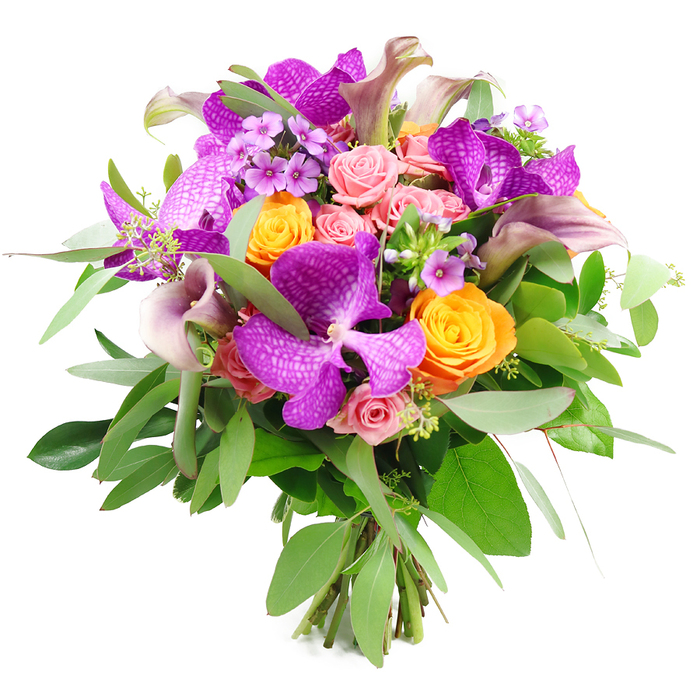 This sophisticated bouquet is captured against a pure white background, its rounded form and intricate mixture of blooms giving it a quietly luxurious presence, perfect for a Stanmore living room or hallway console. Dominating the composition are several large Vanda orchids in an intense fuchsia-purple shade, their velvety petals patterned with a delicate, speckled network that lends each flower an artful, almost hand-painted look. Interwoven among these exotic blooms are vibrant orange roses, firmly cupped and tightly spiralled, their petals glowing in sunny tangerine tones that brighten the entire arrangement. Gentle blush-pink roses nestle between them, some still in bud and others opening into soft, layered rosettes, adding romance and a suggestion of sweet fragrance.
Tall, elegant calla lilies emerge gracefully from the bouquet, shaded in muted lavender, mauve, and plum. Their sleek, trumpet-shaped blooms arc gently above the rounder flowers, echoing the refined silhouettes seen in the gardens around Stanmore Hill. Smaller lavender and lilac filler flowers tuck into the spaces between the larger blossoms, creating subtle flecks of purple that add intricacy and a sense of depth. A lush ring of greenery, including long, silvery eucalyptus leaves and darker, glossy foliage, surrounds the bouquet, giving it structure, cool contrast, and a natural freshness that feels like a breath of air from Stanmore Country Park.
At the base, the stems are neatly gathered and visible, clearly tied in a classic hand-tied style that demonstrates professional skill and thoughtful design. The bouquet overall radiates celebration and tenderness, ideal as a refined anniversary gift delivered to homes around Belmont Circle, a statement piece for a dinner near Marsh Lane, or a meaningful thank-you gesture sent across Stanmore, where same-day delivery keeps the blooms at their most vibrant and fresh.