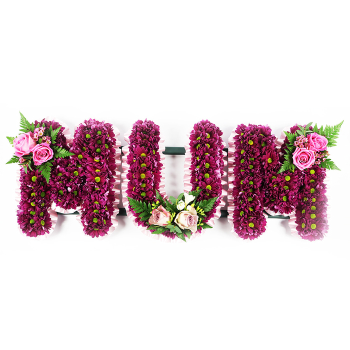 The word MUM is shaped entirely from flowers in this moving funeral tribute, each letter standing proudly against a bright white background that emphasises both colour and form. Strong internal frames support a lavish covering of small fuchsia-purple and deep magenta spray chrysanthemums, laid so closely that they form a continuous, almost velour-like layer. Tiny green centres dot the sea of petals, echoing the soft greens seen around Stanmore's tree-lined streets and quiet residential gardens, and bringing a hint of natural brightness to the saturated tones. Edging every letter, a pale, ruffled pink ribbon is meticulously gathered into soft waves, providing an elegant border that highlights the contours of the word. On the upper left of the first M, two or three fully open soft pink roses, along with several smaller rosebuds, are nestled into a bed of feathery fern fronds and fresh foliage, adding depth and movement. The centre U is graced at its base with a tender spray of blush roses and creamy white blossoms, likely freesia or similar delicate flowers, woven between shiny green leaves to form a gentle cradle within the curve of the letter. The final M echoes the first with its own complementary cluster of vibrant pink roses and fern leaves positioned on the upper right, completing a balanced, mirrored design. Thoughtfully arranged in a style often chosen for services and burials around Stanmore, this bespoke MUM tribute speaks of love, gratitude and lasting remembrance, offering a comforting focus during moments of farewell.