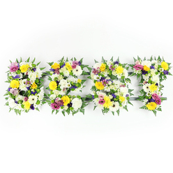 Shot directly from the front with bright, even lighting, this floral composition spells BEST in four large, letter-shaped panels, each expertly sculpted from a dense, tactile mix of fresh blooms and lush foliage. The palette is dominated by clean whites and warm yellows: pillowy white chrysanthemum-style blossoms and delicate ivory gerberas lend a calm purity, while golden yellow roses and gerbera daisies send up sunny notes that feel like captured light. Interspersed among these are soft mauve and purple lisianthus and smaller chrysanthemum clusters that give the letters a quiet, grounding depth, and flashes of fuchsia-pink spray roses or carnations draw the eye with their lively rhythm. Around each letter, generous fern fronds in deep green wrap the edges, their serrated forms softening the typography and creating a living border that contrasts the bright petals. A discreet dark-green or metal support frame can be seen through narrow gaps, especially at the E's middle bar and the T's crosspiece, indicating careful structural work beneath the blooms. The composition is composed for dignity and clarity: against the stark white background each petal and leaf reads with crisp definition. As a local Stanmore florist I picture this arrangement placed near a chapel aisle or at a graveside service by families from Bentley Priory or those walking from Stanmore Common - a visual declaration of remembrance, love, and the comfort of shared memories. Flowers Stanmore prepares pieces like this with attention to freshness and texture, mindful of the mood such a tribute is meant to hold.