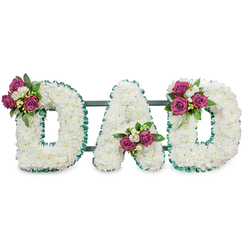 A reverent floral composition sculpts the word DAD in three generous letters, each letter a plush expanse of small, immaculate white chrysanthemums closely clustered to form uninterrupted, cloud-like contours. The white field is crisply edged with bright emerald green ribbon-pleated and slightly ruffled-tracing both outer and inner perimeters to lend definition and a cool, dignified frame. A faint, dark green support bar runs behind the letters, suggesting sturdy construction for standing display at a funeral service or graveside. Each letter is touched with a careful spray of accent blooms: the first D bears a cluster of rich magenta roses and tiny white freesia on its upper left curve; the A nestles a similar grouping into the lower central V; the final D is mirrored with its cluster on the upper right arc. The magenta roses range from tight buds to half-open blooms, their velvet petals set against glossy, deep-green foliage that gives weight and contrast to the white chrysanthemum canvas. The arrangement reads as a conversation between purity and warmth - cool ribbon edges and soft white texture balanced by the affectionate pop of colour - and would carry a gentle scent of rose and freesia in close proximity. Pictured on a plain white background in soft, neutral lighting, the piece feels composed and consoling, ready for display at local Stanmore services or to be placed on a hearse or memorial stand near Canons Park and the surrounding neighbourhoods where families often gather to remember a father.
