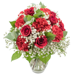 A beautifully composed arrangement of red and white flowers is displayed in a clear glass vase, photographed against a clean white background that highlights its classic elegance. At the heart of the bouquet, deep crimson red roses stand tall, their velvety petals curled into precise spirals that speak of romance and enduring affection. Around them, generous clusters of ruffled red carnations create a plush halo of colour, each bloom made up of countless soft, feathery petals that add fullness and a sense of joyful abundance. Woven between these rich red tones, clouds of white baby's breath bring lightness and contrast, their tiny blossoms scattered along slender stems like delicate lace, giving the whole piece a gentle, dreamy softness. Fresh greenery, from glossy dark rose leaves to rounded eucalyptus in a soft, silvery shade of green, peeks out from among the flowers, adding natural structure and a calming, herbal freshness. The bouquet is arranged into a smooth, rounded dome, every stem thoughtfully placed so that the reds, whites, and greens feel perfectly in balance, showcasing the practiced hand of a local florist used to creating romantic gifts for homes and celebrations all around Stanmore. The simple glass vase, filled with clear water, reveals the carefully prepared stems and gives the composition a grounded, polished look without drawing attention away from the blooms. The overall mood is intimate yet celebratory, ideal for an anniversary dinner in a Stanmore living room, a Valentine's surprise after a stroll through Canons Park, or a special delivery to say I love you or thank you with the timeless combination of red roses, red carnations, and delicate white baby's breath.