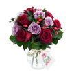A lush, rounded bouquet of freshly opened roses in a striking duet of deep crimson and soft lavender fills the frame, each blossom unfurling velvety petals that catch the light. The arrangement is dense and hand-gathered, with roughly equal numbers of rich burgundy and true-red roses set against clusters of delicate lilac and dusty purple blooms, creating a romantic contrast that reads as both dramatic and tender. Dark, glossy foliage-likely Ruscus or Salal-frames and punctuates the roses, its cool green tones lending depth and a subtle earthy scent that balances the sweet, honeyed fragrance of the roses. Scattered through the mass of petals are small, bright red-orange rose hips, their firm, glossy skins providing a rustic textural punctuation that feels like a late-summer hedgerow tucked into a formal posy. The flowers sit in an antique-effect mercury glass vase: rounded at the base, gently tapering at the neck, its silvered, mottled surface shimmering with a subdued glow as it reflects the white backdrop. A natural raffia tie around the vase's throat adds a hand-finished charm, and a rectangular white gift tag hangs forward with a tiny stylised rose illustration and green-script lettering identifying the sender. Photographed against a pure white background, the colours seem intensified-the crimson grows deeper, the mauves more luminous-evoking feelings of romance, celebration, or thoughtful comfort. As a Stanmore florist would note, this is the sort of bouquet people choose when they want to send warmth and quiet luxury to a loved one or to brighten a home near Stanmore High Street or Stanmore Common.