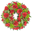 This image shows a perfectly round funeral wreath set against a spotless white background, allowing every flower and leaf in the design to be clearly seen. The wreath itself is densely filled with deep red carnations, whose ruffled, multi-layered petals create a soft, velvety surface that runs all the way around the circle. The carnations vary subtly in height and openness, giving the ring a gently undulating texture rather than a flat, uniform band. Between these rich red blooms sit clusters of lime green button chrysanthemums, small and globe-shaped, with tiny, tightly packed petals that form smooth, domed heads. Their fresh, almost luminous green provides a striking yet harmonious counterpoint to the crimson carnations. Supporting and framing the flowers is a generous collar of foliage: dark leatherleaf ferns extend outwards with slim, feathered fronds, adding a sense of depth and shadow, while variegated pittosporum offers lighter, cream-edged leaves that soften the outer edges of the wreath. Discreetly woven among the greenery is a decorative ribbon in light green with darker diagonal stripes, forming gentle loops that trace the curve of the circle without drawing too much attention. Ideal for a memorial or graveside tribute in Stanmore, perhaps for a service near local landmarks like Canons Park or along Stanmore Hill, this wreath communicates quiet dignity and heartfelt condolence. The careful positioning of flowers and foliage, combined with the calm, even lighting, creates an image of balance and serenity, suited to moments of farewell and remembrance.