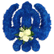 The photograph shows a carefully constructed Sikh Khanda funeral tribute, its iconic shape immediately recognisable and rendered entirely in flowers. Against a clean white background, the emblem appears bold and sculptural, formed from countless royal blue chrysanthemums placed so close together that they create a thick, velvety surface. The circular chakkar, central double-edged sword, and balanced kirpans all emerge clearly from this sea of blue, their outlines crisp and harmonious. The colour is a deep, steady blue, evoking dignity and quiet devotion, much like the peaceful ambience of Stanmore's tree-lined avenues on a calm day. Positioned at the lower section of the central blade is a small, striking accent of white and green. Three elegant white roses, with velvety petals gently unfurling, rest among fine sprays of baby's breath and other tiny blossoms, all supported by rich, dark green foliage that adds depth and life. This central cluster introduces a sense of tenderness and human warmth to the strong symbol, suggesting purity, remembrance, and heartfelt sympathy. The lighting is soft and even, casting delicate shadows that reveal the depth and contours of the arrangement without disturbing its serenity. As a whole, the tribute feels considered and respectful, much like the bespoke designs created by local Stanmore florists for Sikh families marking a loss. Suitable for display in a gurdwara, at a funeral service, or within a home shrine, this floral Khanda offers a visual expression of faith, love, and farewell woven together in fresh blooms.