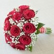 Classic romance takes centre stage in this artfully arranged bouquet, featuring a lavish cluster of deep red roses, each bloom at its richest and most vibrant. Set against a softly textured white surface that allows the bouquet's colours to pop, the arrangement captures the essence of elegance beloved by the Stanmore community. Between the plush rose petals, delicate baby's breath flowers add a wispy layer of snowy white-echoing the light, airy feeling of early morning in the parks that line Stanmore's avenues. A hint of dark green foliage offers occasional glimpses of nature's grounding presence, reminiscent of long walks beneath local canopies. The base of the bouquet is wrapped in a luxurious band of red and white ribbon, twisted and tied into place, accented by a strand of luminous pearls for that extra touch of sophistication. Exposed stems at the handle's end showcase the freshness and careful preparation hallmark to Stanmore's florists. Bathed in fresh, even daylight, the bouquet's rich reds and soft whites come alive-a timeless gift perfect for weddings, anniversaries, or romantic surprises, beautifully reflecting the heartfelt moments and close-knit charm of the Stanmore area.