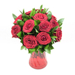 A lush, romantic bouquet of around twelve to fifteen deep crimson red roses stands proudly in a translucent red glass vase, photographed against a spotless white background that makes every petal and leaf glow. Each rose head is fully open yet still plump with life, the velvety petals curling into classic spirals at the centre and unfurling outward in layered whorls of rich ruby red. The blooms are packed closely together in a rounded dome, creating the impression of abundance and luxury, like a concentrated burst of passion caught at its peak. Between the roses, generous sprays of dark, glossy green foliage, likely ruscus, weave in and out, their smooth, pointed leaves adding structure and a cool, verdant contrast to the warmth of the red. The stems are gathered neatly inside an elegant red glass vase with a slightly flared neck and a gently curving body that narrows towards the base, its subtly ribbed or swirled texture catching the light so the glass seems to shimmer. The transparency of the vase allows faint glimpses of stems and changing tones of red, deepening where the glass is thicker. Bright, even studio lighting creates soft shadows and crisp highlights, ensuring no detail is lost. The scene feels timeless and intentional, like a bouquet ready to be delivered to a quiet townhouse off Stanmore Hill for an anniversary surprise, or to a cosy home near Canons Park to mark Valentine's Day. This arrangement, with its intense colour and carefully balanced greenery, conveys deep affection, devotion, and heartfelt romance, a classic red rose gift captured in a single, striking image.