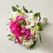 Resting atop a soft, neutral-toned fabric, this hand-crafted bouquet bursts with the lively hues and fine craftsmanship that reflect Stanmore's local floral traditions. Dominating the rounded composition are large, fully opened fuchsia peonies-softly layered and touchably plush-paired elegantly with delicate white Alstroemeria whose petals are painted with intricate maroon filigree for a hint of whimsy. Slender green veronica buds provide uplifting spikes throughout, their zesty hue a reminder of Stanmore's verdant parks and tree-lined avenues. Creamy, bell-shaped accent flowers cushion the more dramatic blossoms, giving the arrangement a light and airy presence, while deep green leaves weave between the flowers, grounding the bright palette. The stems are carefully wrapped in a rich pink satin ribbon, suggesting a tailored, ready-for-the-aisle finish. The bouquet glows in natural daylight, every detail artfully apparent, making it perfect for a Stanmore wedding, festive event, or as a radiant gift. Each thoughtful choice-from the flowers selected to the hand-tied presentation-conveys both a commitment to local freshness and a heartfelt celebration of joyous occasions in and around Stanmore.
