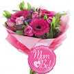 A beautifully coordinated maternity bouquet and balloon set is shown against a clean white background, creating the feeling of a fresh, bright morning in Stanmore. The bouquet itself is a celebration of pink, dominated by bold fuchsia gerbera daisies whose dark central discs contrast sharply with their multi-layered, radiating petals. Between these lively blooms, soft pink roses are tucked at different stages of opening; some remain as neatly folded buds, while others reveal more of their velvety inner whorls, suggesting the gentle progression of new life. Tiny purple filler flowers thread through the arrangement, giving flickers of cool lavender among the warmer tones and adding a textured, almost feathery appearance. Rich green foliage, from slender leaves to broader glossy ones, provides both support and contrast, shaping the bouquet into a rounded, balanced dome that looks ready to be handed to an expectant mum after a baby shower on Stanmore Broadway. The stems are enclosed in layers of pink tissue paper, from light blush to more vibrant tones, with an outer layer of clear cellophane catching the light and giving a soft, gift-like shine. Resting prominently at the front is a round, fuchsia foil balloon with a gently scalloped edge and playful white polka dots scattered evenly over its surface. In elegant white script, the words Mum to Be! are written clearly, with a delicate white heart encircling a smaller pink heart accenting the sentiment. Together, the flowers and balloon project warmth, excitement, and tenderness, perfectly suited to marking the special months before a baby's arrival in Stanmore.