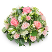 A soft, dome-shaped sympathy arrangement, closely packed and thoughtfully balanced, dominated by gentle pink roses and clusters of pristine white freesia set against a clean white backdrop. The roses range from fully opened garden-style blooms with velvety, spiralled petals to smaller spray roses in paler pinks, creating a subtle gradient from blush to warm salmon at the heart. Intermingled freesia stems introduce upright, bell-like white flowers-some fully unfurled, their pale yellow stamens just visible, others still in tight buds-giving the composition a sense of unfolding hope and a light, sweet scent you almost imagine. The lush greenery creates a verdant cushion: broad, glossy dark-green leaves (think ruscus or salal) push the flowers forward while variegated foliage with creamy edges (likely pittosporum) provides delicate highlights and textural contrast. No stems are visible; the arrangement reads as a refined, cushiony mass, its rounded silhouette casting a soft shadow on the white surface. The natural light in the photo gently sculpts each petal, emphasizing softness and depth and evoking the quiet calm of a chapel or a Well-ordered memorial table. As a local florist's composition for Stanmore families, the piece suggests comfort and remembrance-a peaceful tribute for a funeral service, a celebration of life, or a thoughtful condolence gift-its calm palette and tactile richness offering solace. The craftsmanship shows attention to longevity and mood, an elegant floral language intended to communicate sympathy without words.