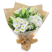 A softly lit bouquet of white and green flowers is shown standing against a plain white background, its form clear and uncluttered, like a still moment of reflection. The central part of the arrangement is filled with numerous white chrysanthemums that resemble daisies, their fine petals layered in delicate circles around vivid yellow-green centres that glow subtly, adding a note of gentle optimism. Rising among these are several tall lily buds, gracefully shaped and not yet open, their surfaces smooth and slightly waxy in appearance, shifting from fresh green to pale, creamy white at the tips. These buds carry a sense of quiet anticipation, as if promising beauty that will unfold slowly over the next few days. Woven throughout are feathery stems of white gypsophila, or baby's breath, the tiny blossoms so numerous they appear like a soft mist surrounding the larger blooms. Deep green foliage wraps around the bouquet, with glossy leaves that curve outward and provide a strong, calm frame, making the white flowers feel even more luminous. The stems are enclosed in rustic brown kraft paper, folded neatly and gently creased, giving the piece a natural, heartfelt character, similar to tributes carried along Stanmore's leafy residential streets to a family gathering. Over the paper, a clear cellophane layer adds protection and a slight reflective shimmer, ensuring the blooms remain fresh for delivery by Flowers Stanmore to local homes, chapels, or crematoria. Tied together firmly at the base, the bouquet feels balanced and composed, expressing sympathy, remembrance, and a soothing sense of peace for anyone in Stanmore who receives it.