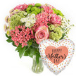 This image presents a joyful Mother's Day bouquet and balloon pairing that could easily be imagined arriving at a home in Stanmore. The setting is a bright white background that highlights the colours and details without distraction. A clear glass vase holds a lush, rounded arrangement of fresh flowers, the stems visible through the water in a way that suggests they have just been arranged by an experienced florist. The bouquet features prominent pink roses, fully open and velvety, their petals edged with a slightly deeper hue, adding a sense of romance and tenderness. Around the roses are clusters of small, coral-pink flowers similar to kalanchoe, each cluster composed of many tiny blossoms that create a rich, intricate texture. Lime-green button chrysanthemums and softly frilled chartreuse blooms punctuate the design, their vivid green tones bringing a refreshing, contemporary twist. Among them, delicate white spray chrysanthemums and small daisy-like flowers add brightness and airiness, catching the light like little stars. Deep green foliage weaves through the arrangement, providing structure, depth, and a natural frame for the more colourful flowers, so the whole bouquet sits in a pleasing domed shape. To the lower right, a heart-shaped foil balloon rests against the edge of the bouquet. Its white background is dotted with irregular metallic spots in gold, silver, and peach, giving a festive confetti effect that echoes the celebratory mood of Mother's Day. In the centre of the balloon, a solid peach heart carries the message HAPPY Mother's DAY in black, mixing bold and script fonts. The combination of fresh, textured blooms and the shiny balloon suggests a warm, complete gift designed to express love and appreciation for mums in Stanmore.